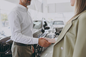 Obraz premium Cropped adult man customer male buyer client wear shirt consulting with salesman shake hand choose auto want buy new automobile in car showroom vehicle salon dealership store motor show. Sales concept