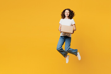 Full body young smiling fun happy courier woman she wears white blank t-shirt casual clothes hold cardboard box jump high isolated on plain yellow orange background studio portrait. Lifestyle concept. - obrazy, fototapety, plakaty