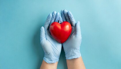 heart disease prevention concept top view photograph of hands in medical gloves holding a heart model on light blue background with copy space for text or advertising placement