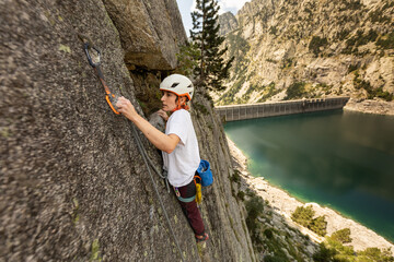 Person climbing in high mountains with yellow jacket rope and helmet in nature, confidence and risk, safety