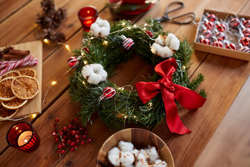 winter holidays, diy and hobby concept - close up of christmas fir wreath and decorations on wooden table