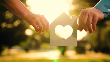 Concept of building house for family, child. Real estate insurance. Paper house in hands at sunset...