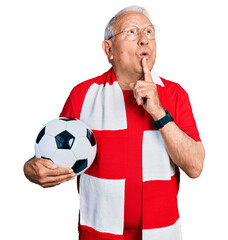 Senior man with grey hair football hooligan holding ball thinking concentrated about doubt with...