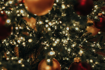 Christmas tree branches with golden red glossy Christmas balls and garland lights. Festive...