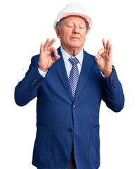 Senior handsome grey-haired man wearing suit and architect hardhat relax and smiling with eyes closed doing meditation gesture with fingers. yoga concept.