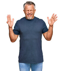 Middle age grey-haired man wearing casual clothes celebrating mad and crazy for success with arms...