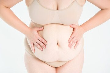 Tummy tuck, flabby skin with stretch marks on a fat belly, plastic surgery concept on gray...