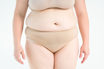 Tummy tuck, flabby skin on a fat belly, plastic surgery concept on gray background