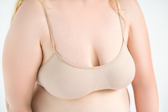 Large natural saggy breasts after breastfeeding in a top bra close-up, big boobs on white background, augmentation and plastic surgery concept