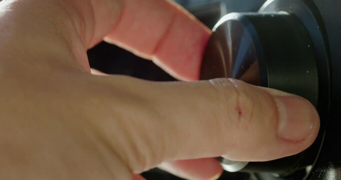 Adjusting the volume level on the receiver. Close-up of fingers turning the knob