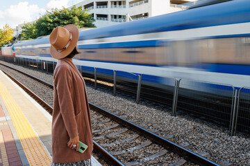 Girl at the railway station. A young woman in a coat and hat stands on the station platform and...