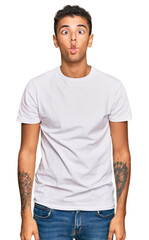 Obraz premium Young handsome african american man wearing casual white tshirt making fish face with lips, crazy and comical gesture. funny expression.