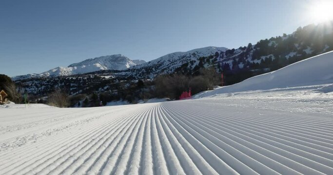 Close-up straight lines rows of freshly groomed ski slope in the morning