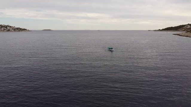 Drone shooting over the water surface. The drone flies over the sea bay in the direction of the oar boat