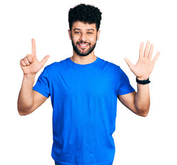 Young arab man with beard wearing casual blue t shirt showing and pointing up with fingers number seven while smiling confident and happy.