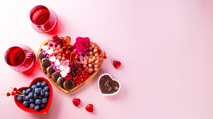 Snack board in shape of heart with berries, chocolate and sweets for Valentine's Day and two...