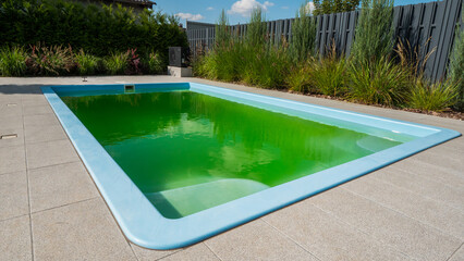 Green water in a home pool in the backyard of a house. Bloomed due to incorrect dosage of chemicals