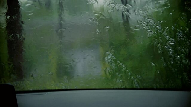 Heavy rain . Dripping drops on car window