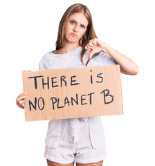 Young beautiful blonde woman holding there is no planet b banner with angry face, negative sign showing dislike with thumbs down, rejection concept