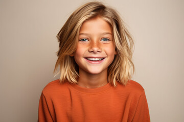A young boy with long blonde hair is smiling for the camera