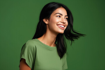Fototapeta premium A woman in a green shirt is smiling with her hair blowing in the wind