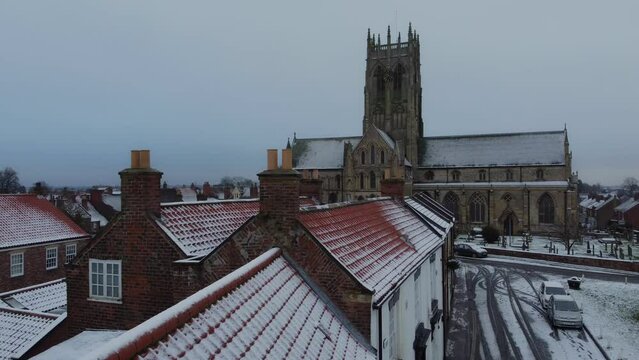 Drone shot. Snow winter scene. Church of England. Parish church in English countryside. Christian church worship UK. 