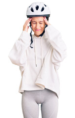 Beautiful brunette young woman wearing bike helmet and sporty clothes with hand on head for pain in head because stress. suffering migraine.