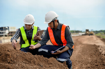 Highway engineers touch and inspect laterite soil for construction improvement base road work,...