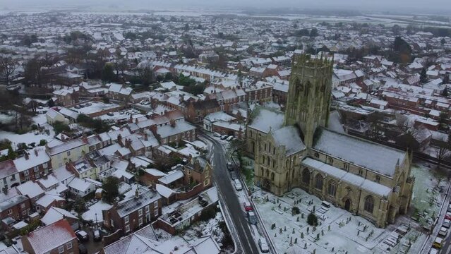 Drone shot. Snow winter scene. Church of England. Parish church in English countryside. Christian church worship UK. 