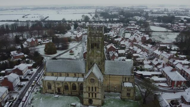Drone shot. Snow winter scene. Church of England. Parish church in English countryside. Christian church worship UK. 
