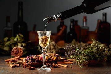 Yellow herbal liquor or mixture is poured from a vintage bottle into a glass.