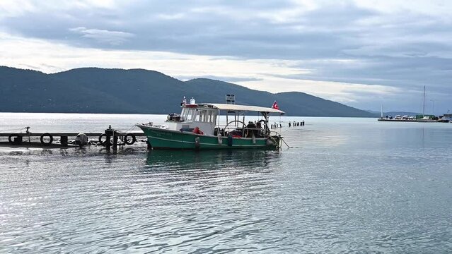 A cloudy day in Akyaka Azmak. Magnificent view of Gokova and the sea. Reflections in the water and daily tour boats. White boats lined up in the harbor in the background.  Azmak, Akyaka MUGLA.