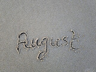 August als Wort im Strandsand