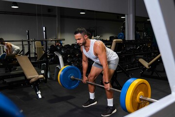 Fototapeta na wymiar Strong Hispanic man deadlift at a gym.
