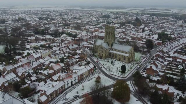Drone shot. Snow winter scene. Church of England. Parish church in English countryside. Christian church worship UK. 