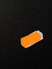 Orange label for discounted merchandise glued on black paper box, close up