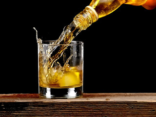 Whiskey pouring in a glass from a bottle, close up on black background