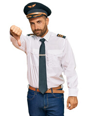 Handsome man with beard wearing airplane pilot uniform looking unhappy and angry showing rejection and negative with thumbs down gesture. bad expression.