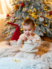 A Joyful Christmas Surprise: Baby Mesmerized by the Sparkling Tree Lights. A baby sitting in front...