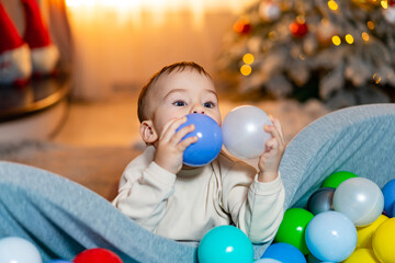 Obraz premium A Joyful Baby Surrounded by Colorful Balloons in a Fun Ball Pit. A baby sitting in a ball pit with balloons