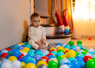 Fototapeta na wymiar A Joyful Baby Surrounded by Colorful Balloons. A baby sitting on the floor surrounded by balloons