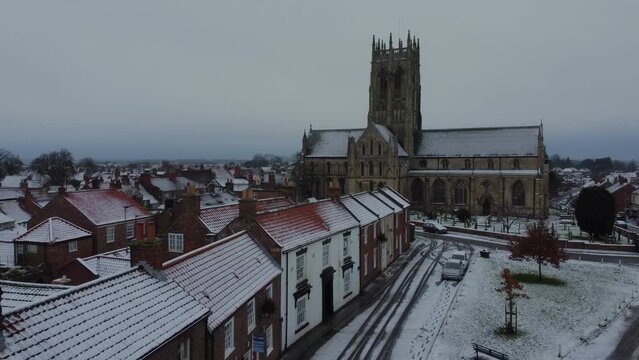 Drone shot. Snow winter scene. Church of England. Parish church in English countryside. Christian church worship UK. 