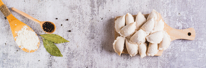 Frozen raw dumplings with potatoes on a cutting board on the table top view web banner