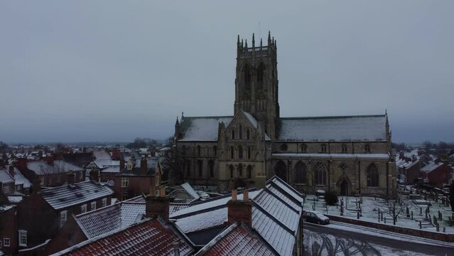 Drone shot. Snow winter scene. Church of England. Parish church in English countryside. Christian church worship UK. 