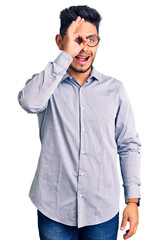 Fototapeta premium Handsome latin american young man wearing business clothes and glasses smiling happy doing ok sign with hand on eye looking through fingers