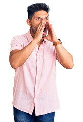 Handsome latin american young man wearing casual summer shirt shouting angry out loud with hands over mouth