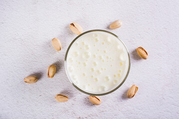 Close up of lactose-free pistachio milk in a glass and nuts on the table top view
