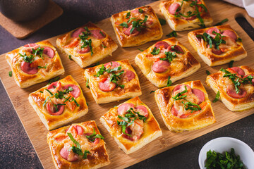 Snack mini pizza with sausages, tomato and cheese on a wooden board