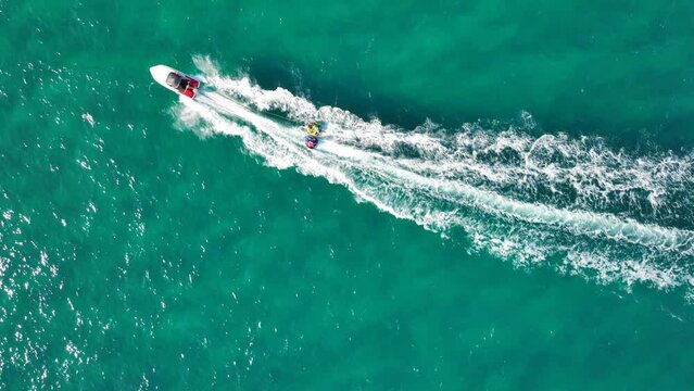 Aerial drone video of extreme inflatable towable tube cruising in high speed attached on powerboat with children riding, watersport