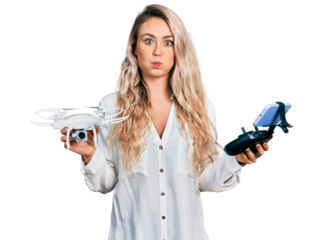 Young blonde woman holding television remote control puffing cheeks with funny face. mouth inflated with air, catching air.